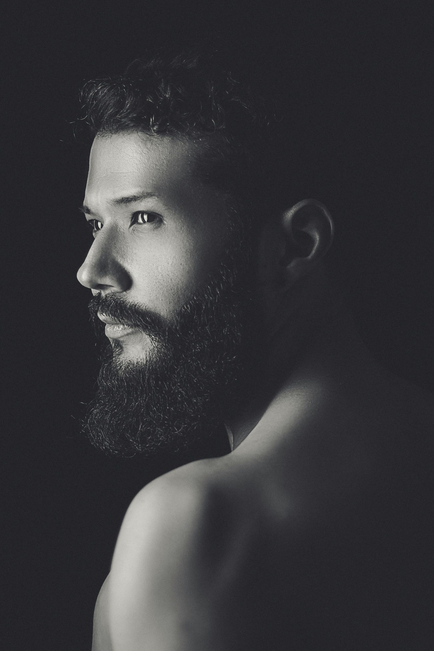 Portrait premium d’un homme asiatique avec barbe discrète, éclairage studio.