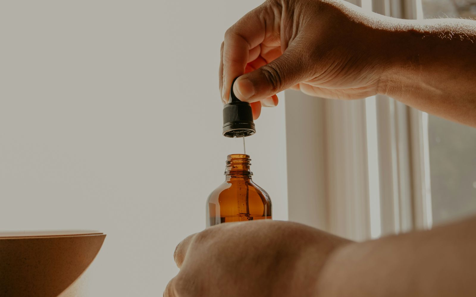 Main masculine utilisant une pipette pour appliquer une huile à barbe bio